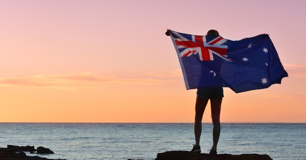 オーストラリアの旗を持って海辺に立つ人